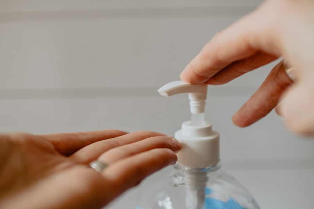 hand beneath the nozzle of hand sanitizer